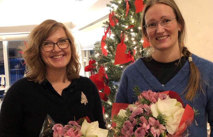 To kvinner med blomsterbuketter foran juletre