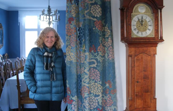 Kvinne i blå jakke ved siden av veggur