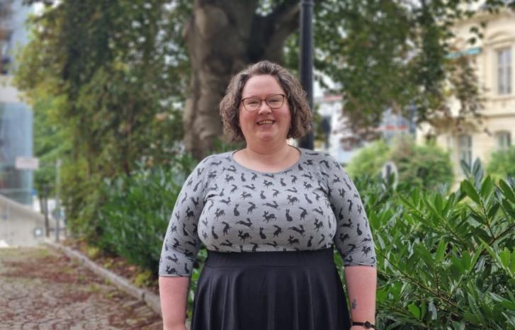 Sunniva Árja Tobiasen, stipendiat ved senter for kvinne- og kjønnsforskning ved Universitetet i Bergen fotografert omgitt av grønne trær