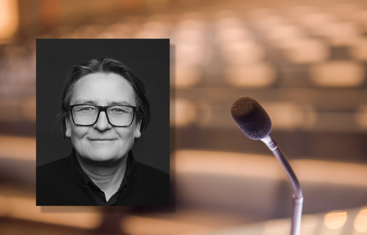 Portrettfoto av Ragnhild Hennum, dekan ved UiO, mot bakgrunn med mikrofon og tomme stolrader