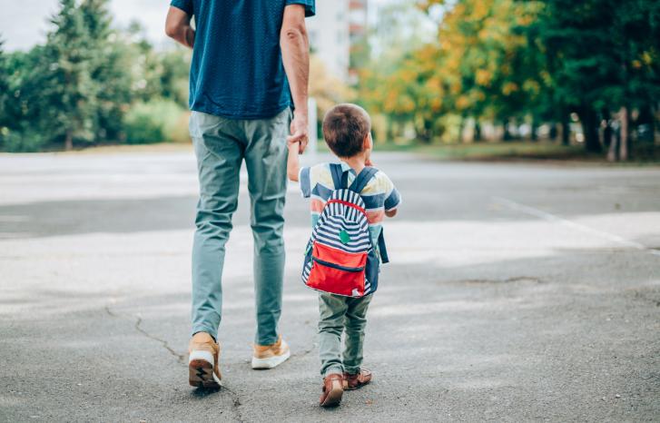 En far følger et lite barn til skolen