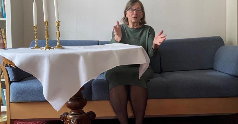 Charlotte Koren sittende i blå sofa ved et bord med hvit duk