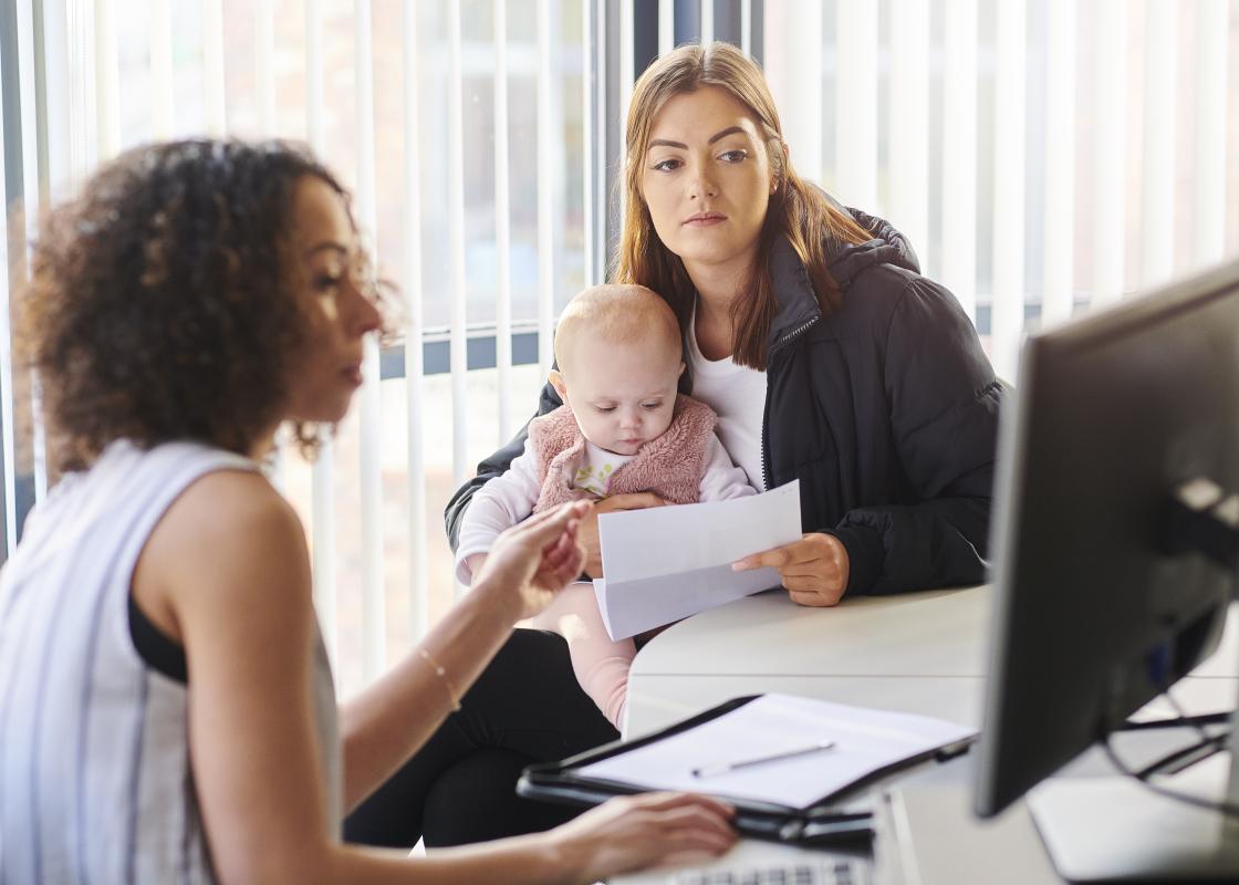To kvinner, en med et barn på fanget, gjør papirarbeid