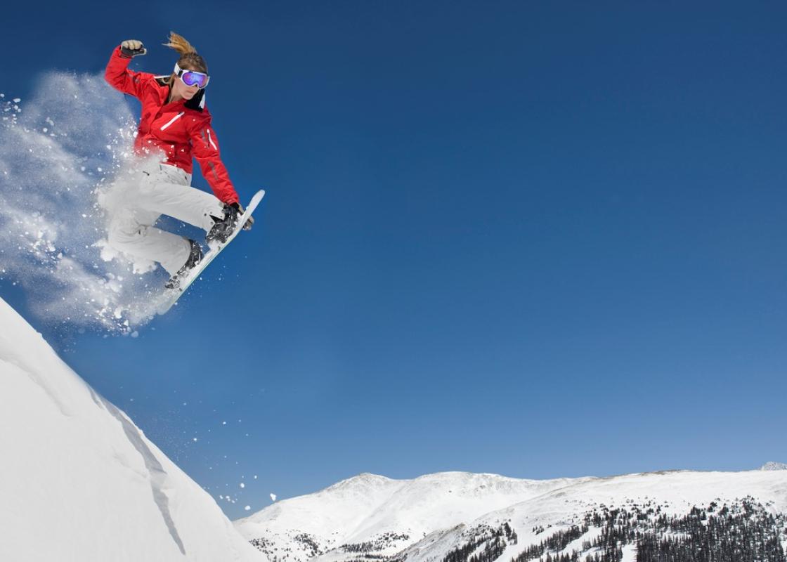 Jente kjører snowboard på fjelltopp