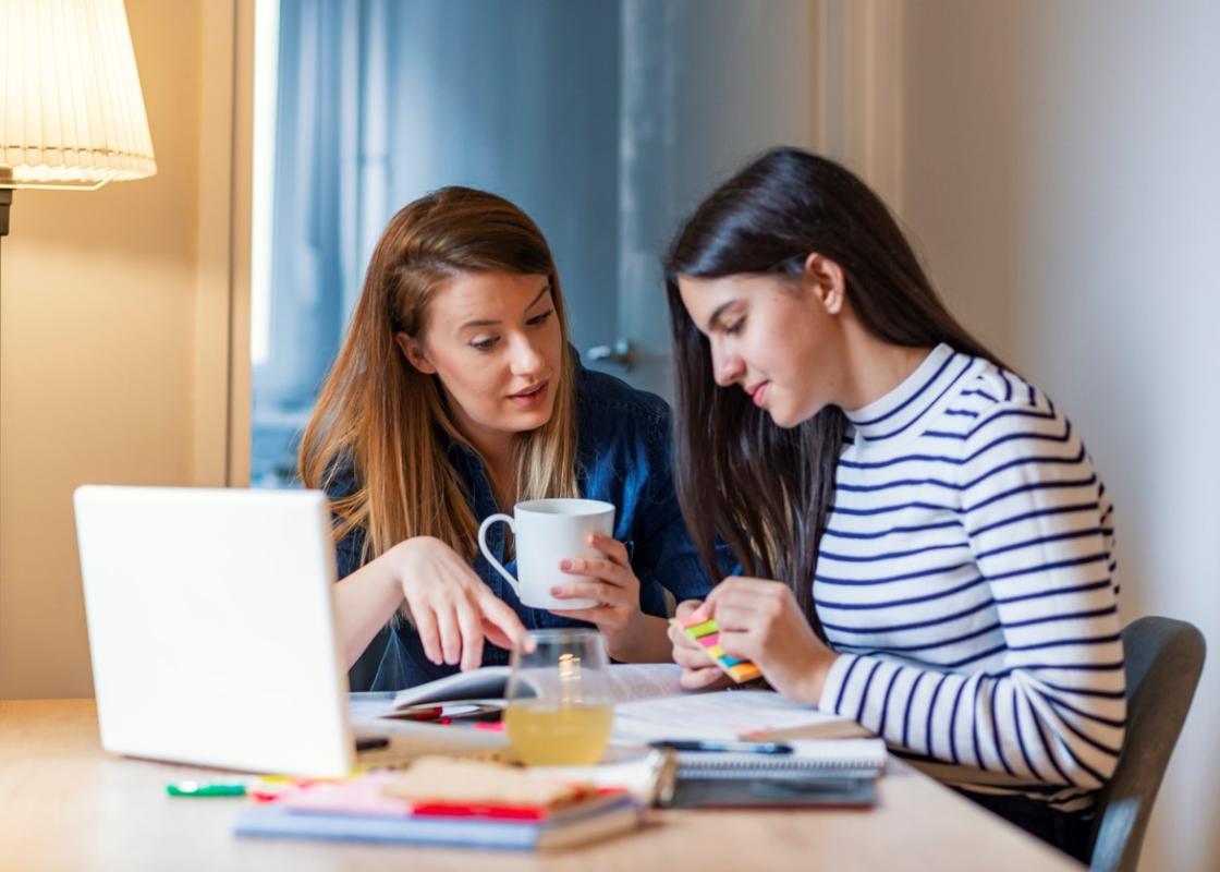Ung mor og tenåringsdatter sitter ved en pc og diskuterer