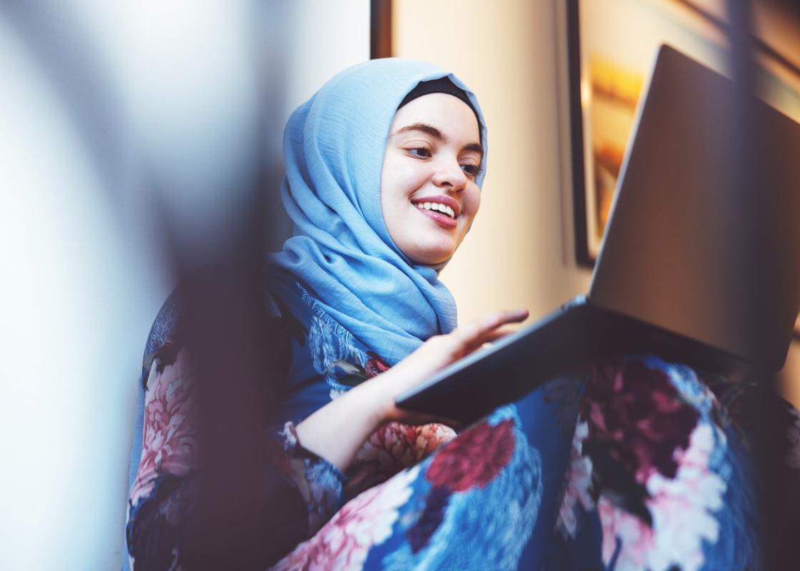 Ung kvinne fra Midtøsten med hijab skriver på pc