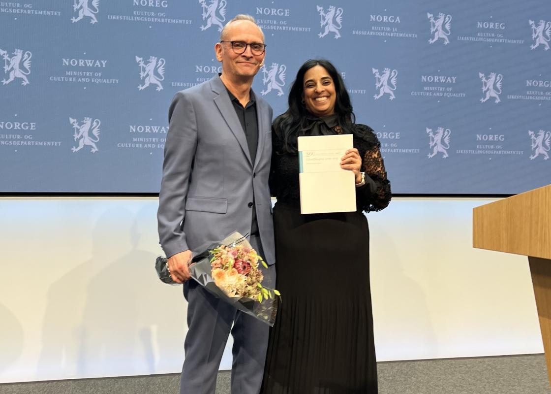 Leder av mannsutvalget Claus Jervell, gir rapporten til statsråd Lubna Jaffery