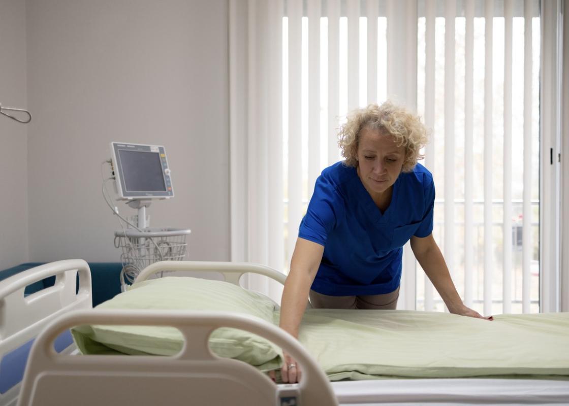 Voksen kvinne rer opp sykehusseng