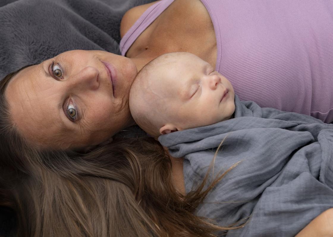 Godt voksen kvinne ligger med sovende baby på brystet