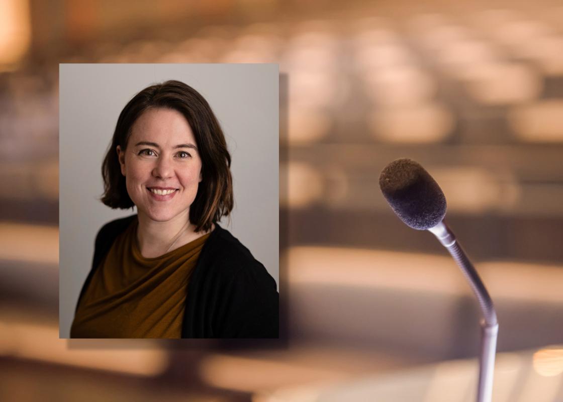 Portrettfoto av Siri Øyslebø Sørensen, professor ved NTNU, med et bakgrunnsbilde av et tomt auditorium