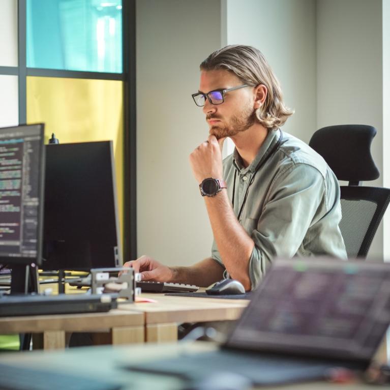 Ung mann med briller foran pc-skjerm