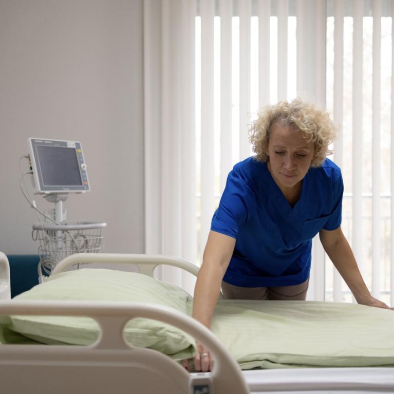 Voksen kvinne rer opp sykehusseng